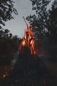 View of a large traditional bonfire burning brightly with glowing embers and sparks rising into the night sky in a forest setting in Laane County, Estonia.