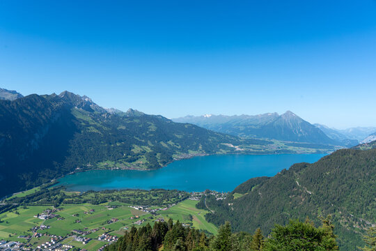 View of Harder Kulm overlooking the turquoise waters of Lake Thun, surrounded by lush green valleys and the Swiss Alps in Unterseen, Canton of Bern, Switzerland.