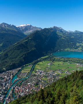 View of Harder Kulm overlooking the town of Unterseen, the Aare river, and Lake Thun nestled among the Swiss Alps under a clear blue sky. Unterseen, Canton of Bern, Switzerland.
