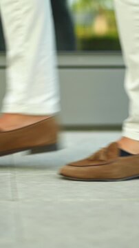 Stylish man in loafers walking on urban sidewalk