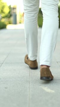 Man in white pants walking on a city sidewalk