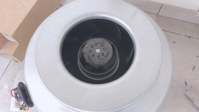Duct fan with rotating impeller runs on the floor before installation