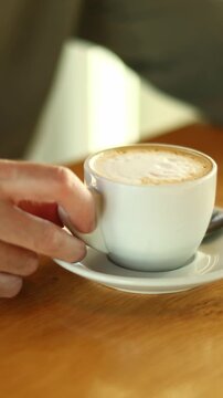Man holding a cappuccino cup in a cafe during morning break