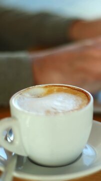 Man typing on laptop while drinking coffee in a cafe