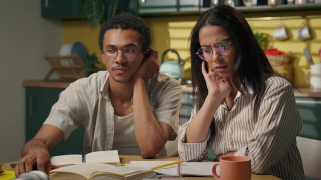 Thoughtful African American guy and Latina girl studying at home kitchen pondering homework problem multiethnic high school students thinking together brainstorm project task pensive gen z classmates