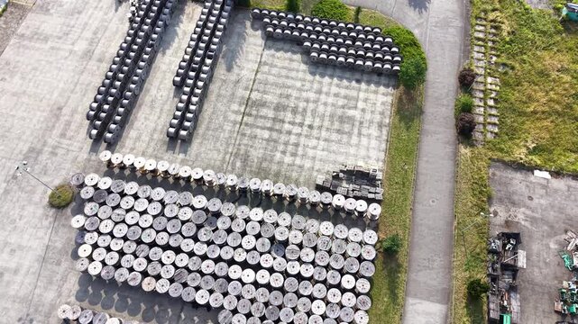 Aerial view of a warehouse displaying a large arrangement of wooden cable reels organized in rows, showcasing a systematic layout across the expansive concrete surface. Industrial place