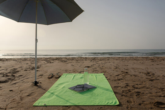 Vertical green beach towel with book sunglasses and flip flops