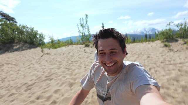 Happy couple selfie view running and having fun on a sand dune in Carcross desert