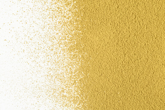 Golden hojicha powder fades into scattered grains across white copy space and forms warm textured background for tea branding.