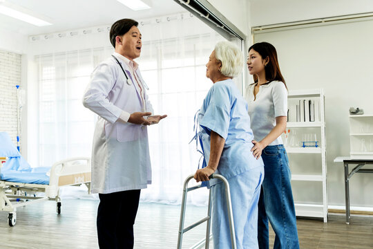 Doctor discusses recovery plan with an elderly patient using a walker as a family member listens in a bright hospital room.