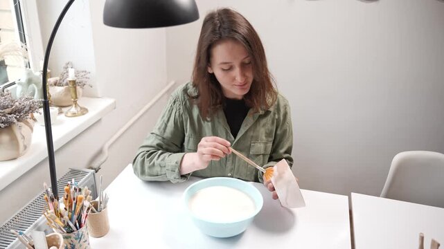 Artisan glazing a bisque ceramic bowl with a wide studio paintbrush. Artist applying thick glaze to a handmade clay bowl for an artistic finish 4k video