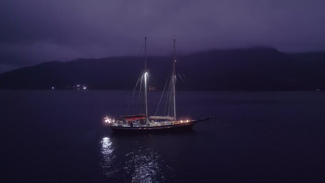 Big expeditional sailing boat anchored in the calm sea at night. Drone night shot
