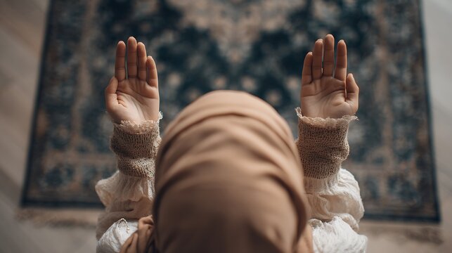 Woman in hijab praying with hands raised in a mosque
