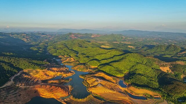 Drone shot of Tad Ma Waterfall flowing through a productive agricultural landscape with rice paddies, livestock farms, and well-irrigated fields in Vientiane, Laos.