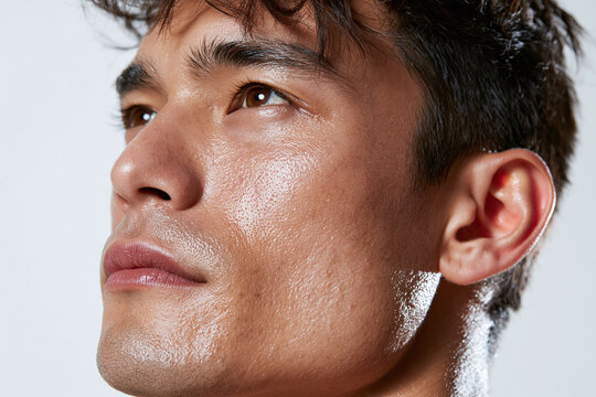 Clinical macro portrait of Asian man jawline with healthy skin texture and subtle shine conveying confidence and vitality