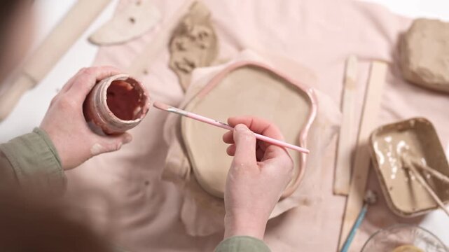 Handmade Ceramic Pottery Crafting Process 4K Video Slow Motion. Artist manually shapes a clay vessel on a workshop table, assembling an artistic ceramic piece