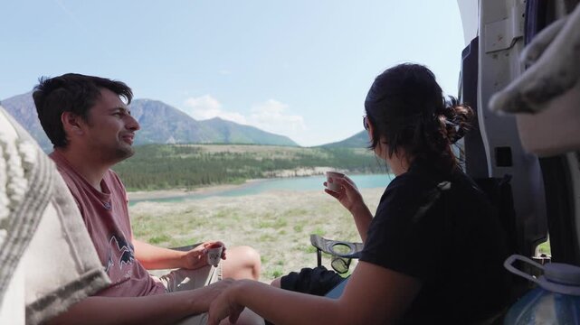 Couple enjoying espresso coffee by camper van with lake and mountains view