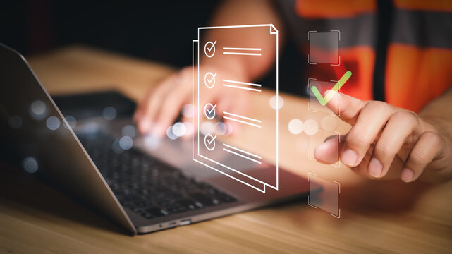 Industrial worker pointing at virtual checkmark box on glowing digital document. Online compliance test, safety inspection form, and digital transformation concept in modern factory.