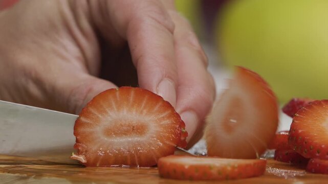 Chef using small knife to slice through juicy strawberry - extra closeup