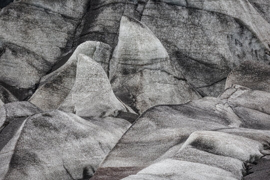 View of Jokulsarlon glacier ice formations with textured surfaces and dark volcanic ash deposits, Sveitarfelagid Hornaf, Iceland.