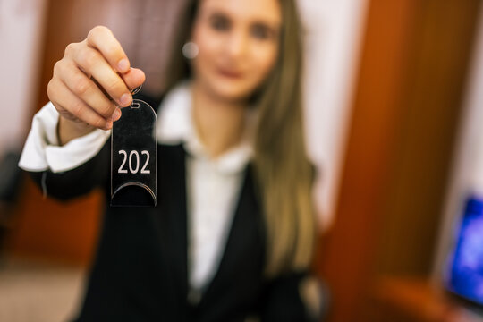 Close-up of hotel receptionist holding room key card toward the camera