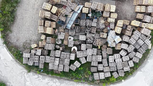 Aerial view of stacked wooden pallets and boxes in a storage area, showcasing the organized arrangement and varying orientations of the materials across the frames