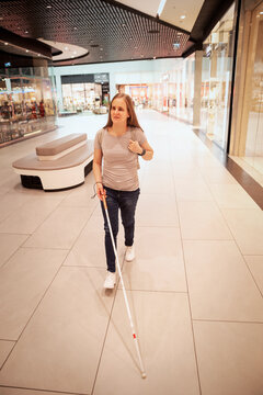 Visually impaired woman with white cane walking in a modern shopping mall