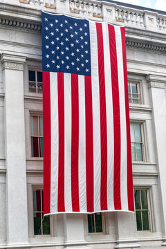 Large American flag dominates the classical US Treasury Building exterior in Washington DC.