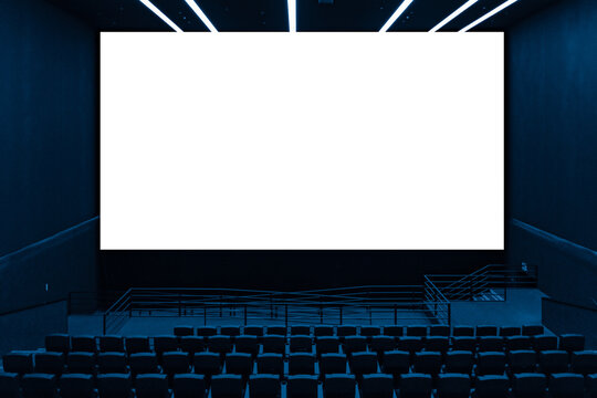 Cinema hall interior view with rows of empty dark seats looking at large blank screen with transparent area for image replacement