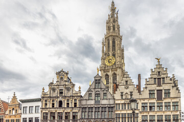 Obraz premium Antwerp town in Belgium, Europe. Dramatic View of Historic European Town Square with Grand Bell Tower and Ornate Gable Houses Under a Cloudy Sky