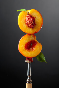 Two halves of a fresh nectarine on a fork.