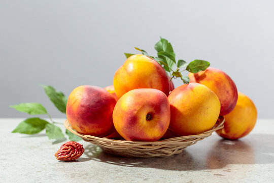Fresh nectarines with leaves on a kitchen table.