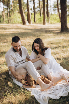 Family enjoying a summer picnic in a pine forest, parents and child bonding together outdoors, happy childhood moments