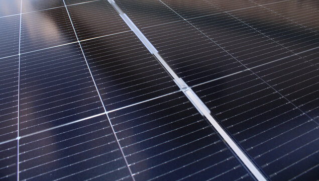 Close-up of solar panels displaying a technical grid pattern and reflective surface in a diagonal perspective, ideal for renewable energy themes