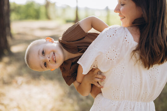 Happy mother holding cheerful son up in a playful summer moment outdoors, enjoying family love and childhood fun