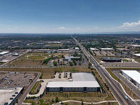 Aerial view of industrial warehouses, commercial buildings, and road networks in the suburban landscape of Thornton, Colorado, United States.