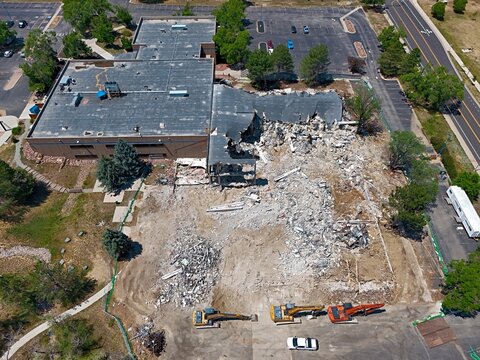 Aerial view of a building demolition site with heavy machinery, excavators, and debris in Thornton, Colorado, United States.