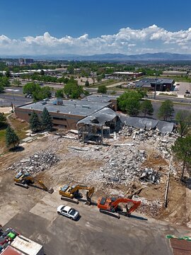 Aerial view of a demolition site with heavy machinery including excavators working on a building structure in Thornton, Colorado, United States.