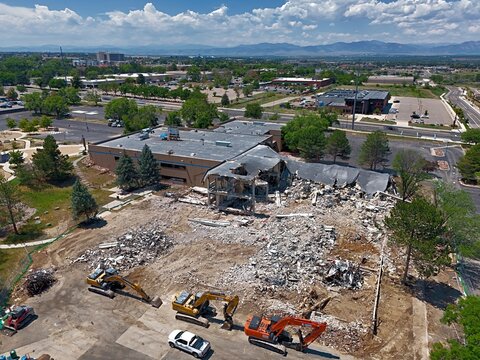 Aerial view of a building demolition site with heavy machinery, excavators, and debris in a suburban area in Thornton, Colorado, United States.