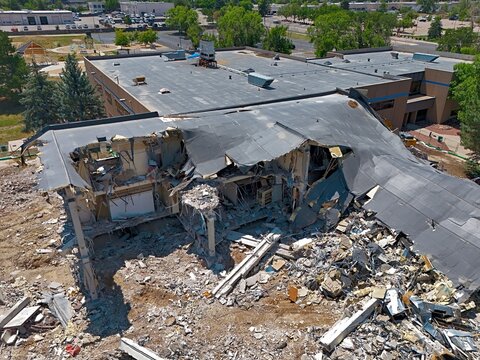 Aerial view of a building undergoing demolition with exposed structural elements, piles of debris, and heavy machinery on site in Thornton, Colorado, United States.