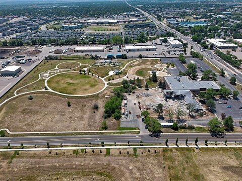 Aerial view of a park with a circular lawn, walking paths, and a building under demolition in Thornton, Colorado, United States.