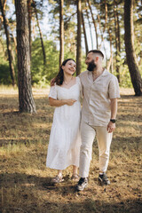 Fototapeta premium Couple walking and smiling in a sunny pine forest, enjoying summer vacation and togetherness