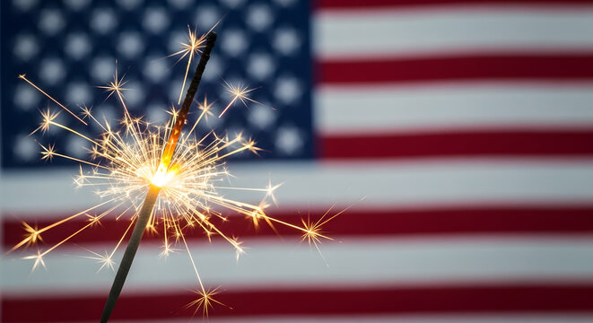 Bright sparkler burning against blurred United States flag background