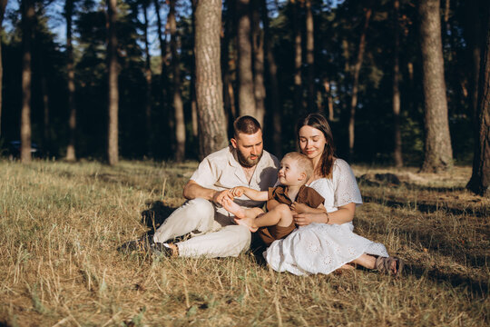 Family bonding in forest, parents and child enjoying summer nature, happy togetherness outdoors in sunlight