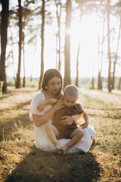 Mother embracing son in a warm summer forest, showing love, care, and family bond during golden hour