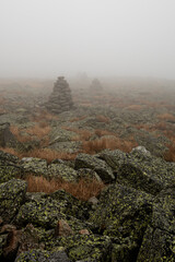 Obraz premium Foggy mountain landscape with rock cairns, navigation and wilderness