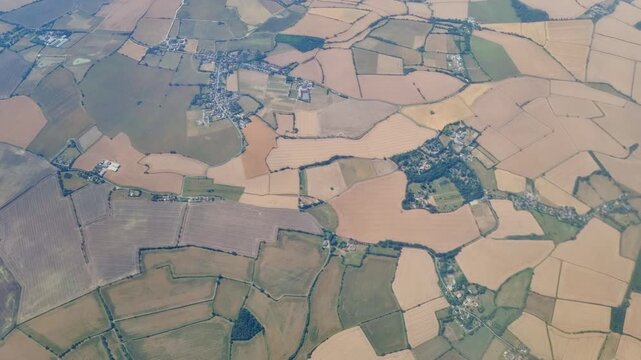 Aerial view of patchwork farmland with fields and rural settlements, showcasing agricultural land use and landscape patterns across rolling hills in a countryside region