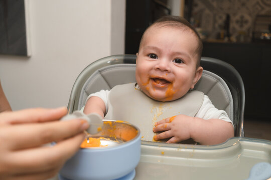 Beb&eacute; ni&ntilde;o comiendo papilla de zanahoria en la silla