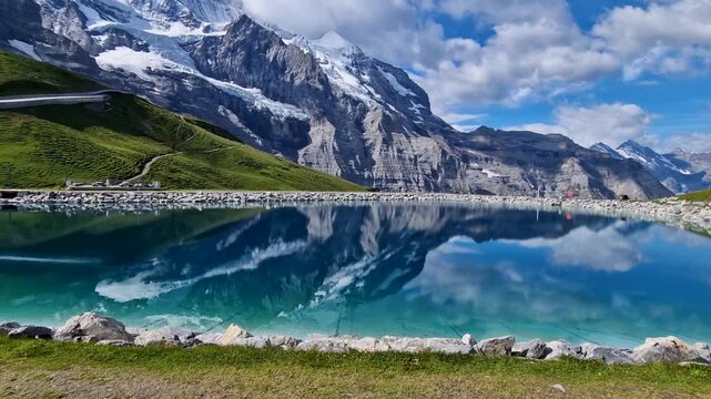 Fallboden Lake Jungfrau region Switzerland 4K. Mirror reflection of Eiger M&ouml;nch snowy peaks in turquoise water with wooden benches in morning. Scenic alps landscape travel b-roll stock video