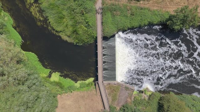 Drone overhead view of River Anker weir with cascading water to control water flow in Tamworth, Staffordshire, UK